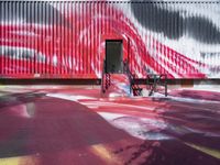 the red wall with black and white designs is near a park bench that has wheels in it