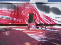 the red wall with black and white designs is near a park bench that has wheels in it