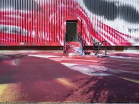 the red wall with black and white designs is near a park bench that has wheels in it