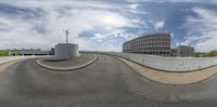 a big building on the left side of the road that is empty of traffic and has a blue sky in the background