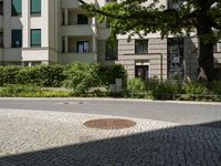 the yellow fire hydrant is located on the corner of this square of paved stones