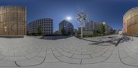 a 360 - camera image shows people riding bicycles in a circular park surrounded by tall buildings