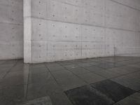 a skateboard on a sidewalk next to a building with a wall behind it on a rainy day