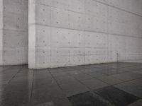 a skateboard on a sidewalk next to a building with a wall behind it on a rainy day