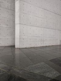 a skateboard on a sidewalk next to a building with a wall behind it on a rainy day