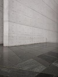 a skateboard on a sidewalk next to a building with a wall behind it on a rainy day