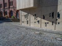 cobblestone driveway surrounded by modern buildings on sunny day with sun reflecting onto the windows