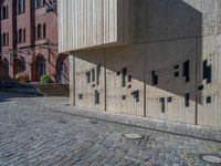 cobblestone driveway surrounded by modern buildings on sunny day with sun reflecting onto the windows