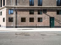 a brick building with three windows on top of it and a green door at the top