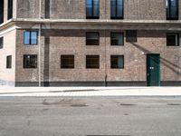 a brick building with three windows on top of it and a green door at the top