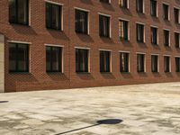 an empty courtyard that is near a brick building and several windows has a street sign on the sidewalk