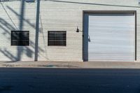 a empty side walk with closed garage doors and one fire hydrant in front of an urban brick wall