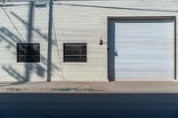 a empty side walk with closed garage doors and one fire hydrant in front of an urban brick wall