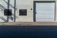 a empty side walk with closed garage doors and one fire hydrant in front of an urban brick wall