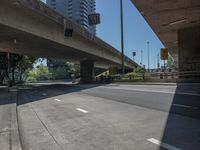 an empty street with lots of traffic underneath a large overpass over a street in a city