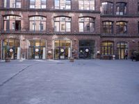 a building with many windows and doors on the sidewalk as a man stands outside near the door