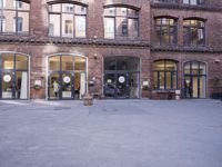 a building with many windows and doors on the sidewalk as a man stands outside near the door