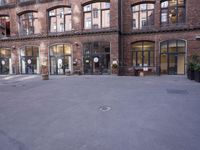 a building with many windows and doors on the sidewalk as a man stands outside near the door