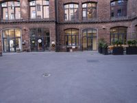 a building with many windows and doors on the sidewalk as a man stands outside near the door