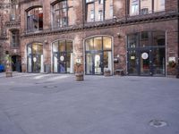 a building with many windows and doors on the sidewalk as a man stands outside near the door