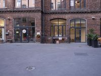 a building with many windows and doors on the sidewalk as a man stands outside near the door