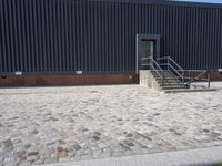a brick building with glass windows and sidewalk leading to it and a black fire hydrant
