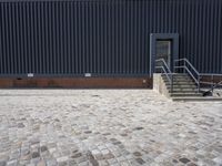 a brick building with glass windows and sidewalk leading to it and a black fire hydrant