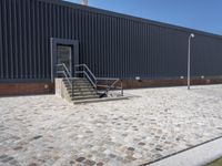 a brick building with glass windows and sidewalk leading to it and a black fire hydrant