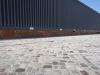 a brick building with glass windows and sidewalk leading to it and a black fire hydrant