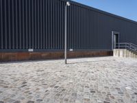 a brick building with glass windows and sidewalk leading to it and a black fire hydrant