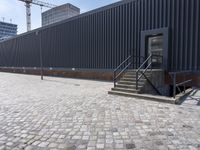 a brick building with glass windows and sidewalk leading to it and a black fire hydrant