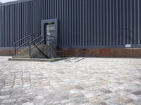 a brick building with glass windows and sidewalk leading to it and a black fire hydrant