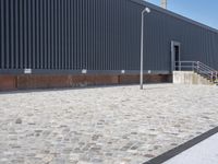 a brick building with glass windows and sidewalk leading to it and a black fire hydrant