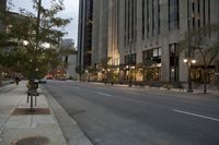 a road runs down the side of the street from an urban building at dusk with trees on both sides of it