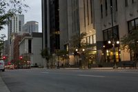 a road runs down the side of the street from an urban building at dusk with trees on both sides of it