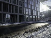 the sun shines brightly in the windows and snow covering street in front of the large building