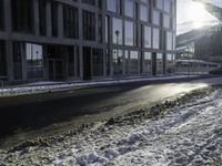 the sun shines brightly in the windows and snow covering street in front of the large building