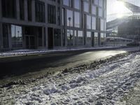 the sun shines brightly in the windows and snow covering street in front of the large building