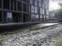 the sun shines brightly in the windows and snow covering street in front of the large building