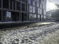 the sun shines brightly in the windows and snow covering street in front of the large building
