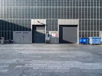 a building with an exit way and some garbage cans outside of it in front of the building