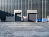 a building with an exit way and some garbage cans outside of it in front of the building