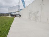 a skateboarder is riding on the sidewalk by the building of an art museum