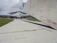 a skateboarder is riding on the sidewalk by the building of an art museum