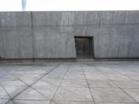 a large gray building with some concrete walls and a closed door in it's center