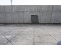 a large gray building with some concrete walls and a closed door in it's center