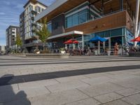 people are sitting at tables outside a restaurant that is built with glass walls and a wood structure