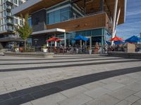 people are sitting at tables outside a restaurant that is built with glass walls and a wood structure