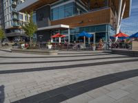 people are sitting at tables outside a restaurant that is built with glass walls and a wood structure