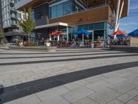 people are sitting at tables outside a restaurant that is built with glass walls and a wood structure